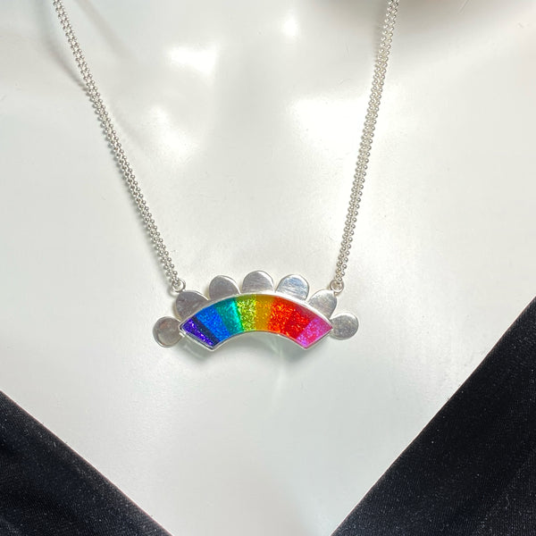 rainbow colored glass hand cut rainbow shape with silver flange cut out clouds necklace, fused glass, glass jewelry, glass and silver jewelry, handmade, handcrafted, American Craft, hand fabricated jewelry, hand fabricated jewellery, Athen, Georgia, colorful jewelry, sparkle, bullseye glass, dichroic glass, art jewelry