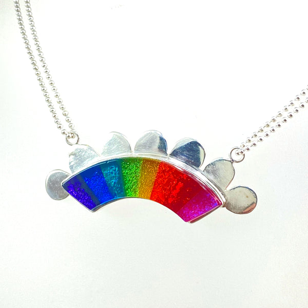 rainbow colored glass hand cut rainbow shape with silver flange cut out clouds necklace, fused glass, glass jewelry, glass and silver jewelry, handmade, handcrafted, American Craft, hand fabricated jewelry, hand fabricated jewellery, Athen, Georgia, colorful jewelry, sparkle, bullseye glass, dichroic glass, art jewelry