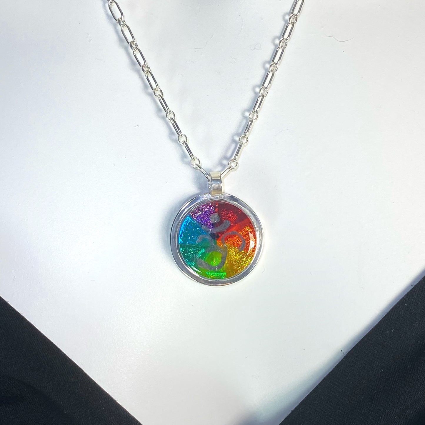 kaleidoscope circle necklace in rainbow colors, silver luster painted OHM symbol,fused glass, glass jewelry, glass and silver jewelry, handmade, handcrafted, American Craft, hand fabricated jewelry, hand fabricated jewellery, Athen, Georgia, colorful jewelry, sparkle, bullseye glass, dichroic glass, art jewelry